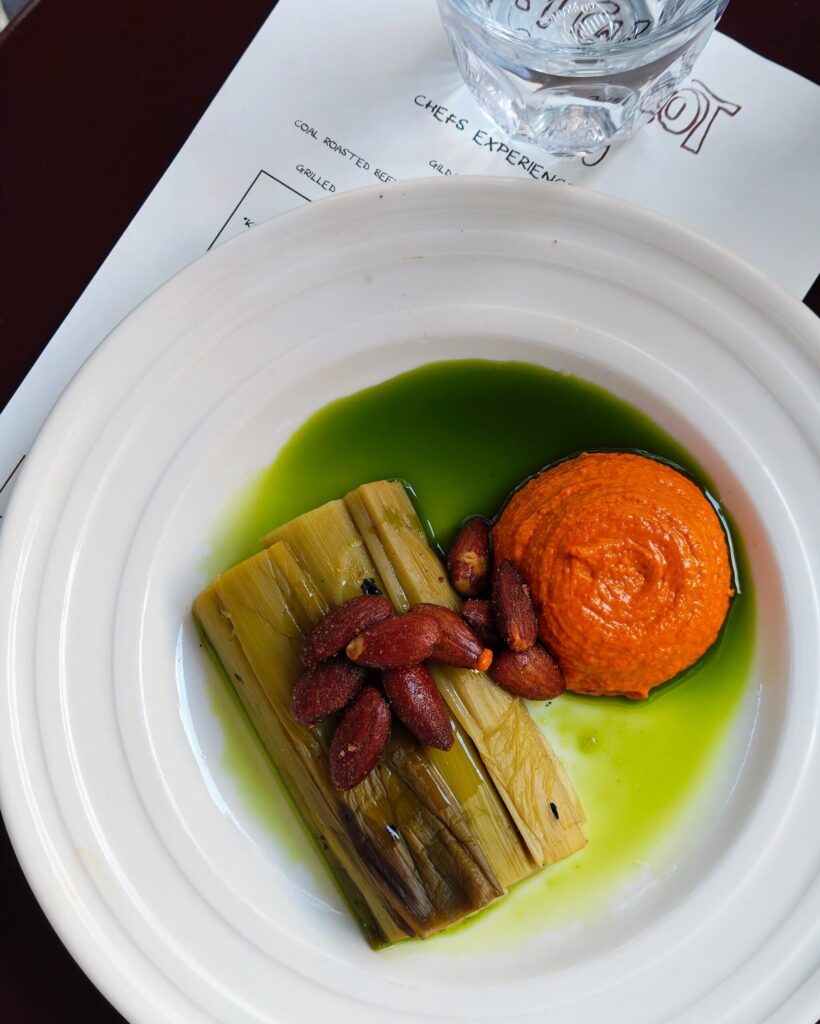 Coal-roasted leeks - Pepper romesco sauce and almonds at Holy Carrot Bistro
